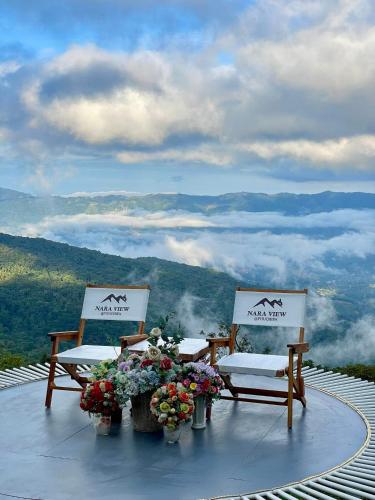 two chairs sitting on top of a mountain with clouds at Naraview at phuchifa in Thoeng