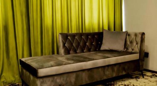 a couch sitting in front of green curtains at Borrman Hotel Jining High-tech Huangtun in Jining