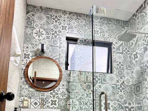 a bathroom with a mirror and a tile wall at Cabaña Montez in Puente de las Cuevas