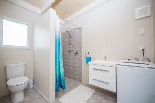 a bathroom with a shower and a toilet and a sink at Frederick and Ngamata's Beach House in Rarotonga