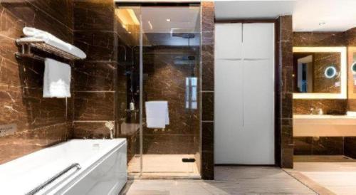 a bathroom with a tub and a shower with a door at Borrman Hotel Wuhan Hankou Railway Station Metro Station in Wuhan