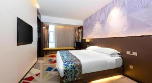 a bedroom with a bed and a flat screen tv at Borrman Hotel Wuhan Hankou Railway Station Metro Station in Wuhan