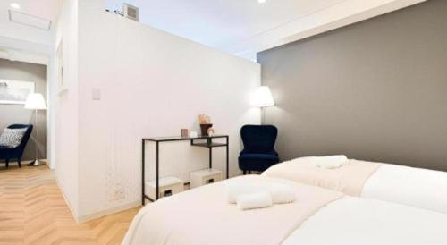 a white bedroom with two beds and a blue chair at HOSTEL LUND I -Oimachi- in Tokyo