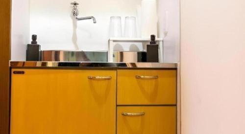 a kitchen with yellow cabinets and a sink at HOSTEL LUND I -Oimachi- in Tokyo