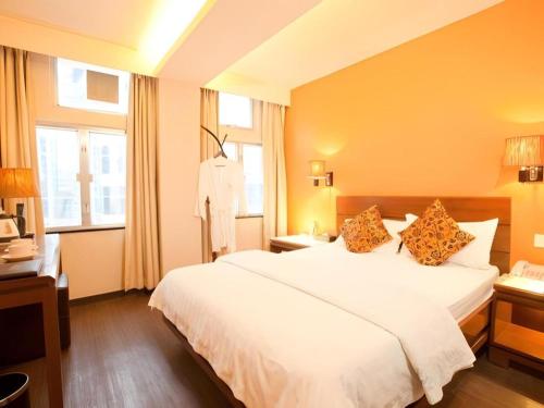 a bedroom with a large white bed and windows at Sunny Day Hotel in Hong Kong