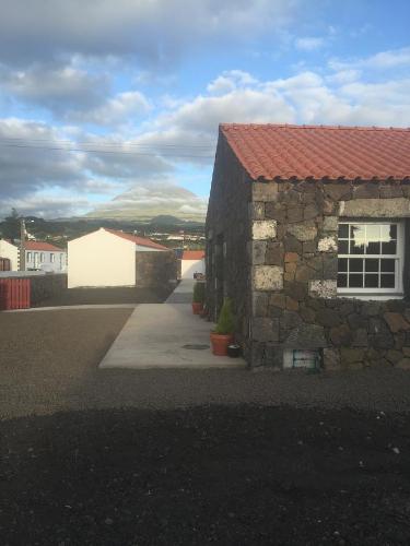 a stone building with a red roof on a street at Casas do Verdelho in Madalena