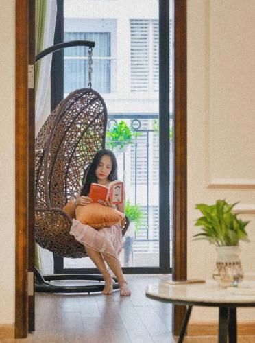 a woman sitting in a chair reading a book at Alice's home Times city in Hanoi