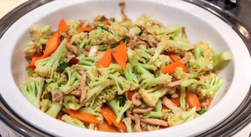 a bowl of food with broccoli and carrots at Echarm Hotel Wuhan Gaotie Jianshe 2nd Road Metro Exit in Wuhan