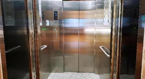a metal elevator with glass doors in a room at Echarm Hotel Wuhan Gaotie Jianshe 2nd Road Metro Exit in Wuhan