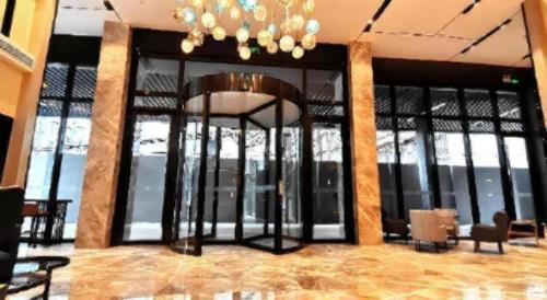 a lobby with glass doors and a chandelier at Echarm Hotel Wuhan Gaotie Jianshe 2nd Road Metro Exit in Wuhan