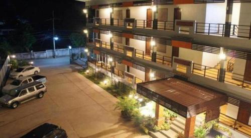 an apartment building with two cars parked in a parking lot at Nan Treasure Hotel in Nan