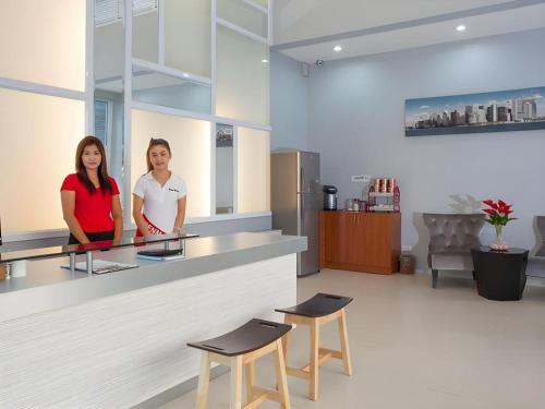 two women standing behind a counter in a kitchen at Soontree House Hotel in Udon Thani