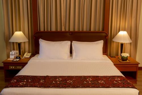 a bed in a hotel room with two lamps on tables at CS Pattani Hotel in Ban Ru Sa Mi Lae