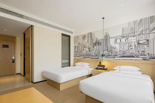 two beds in a room with a painting on the wall at City Comfort Inn Hengyang East Station Linghu Wanda Industry College in Xiantang