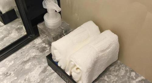 a pile of towels sitting on a counter next to a mirror at Echarm Hotel Shenzhen World Exhibition and Convention Center in Shenzhen