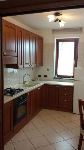 a kitchen with wooden cabinets and a sink and a window at Cartaromana House in Ischia