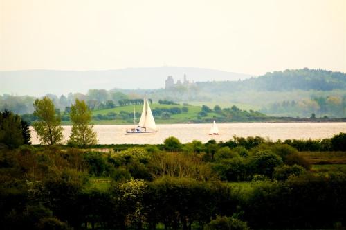 two sailboats on a river with a castle in the distance at Bunratty Meadows Bed & Breakfast in Bunratty