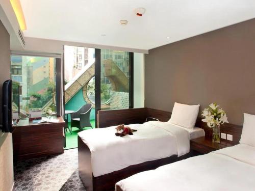 a bedroom with two beds with a teddy bear sitting on the bed at J Link Hotel in Hong Kong