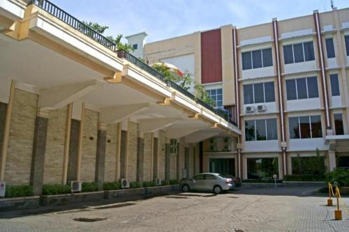a car parked in front of a large building at Karlita Hotel Tegal in Tegal