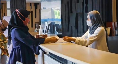 a woman in a hijab standing at a counter at Karlita Hotel Tegal in Tegal
