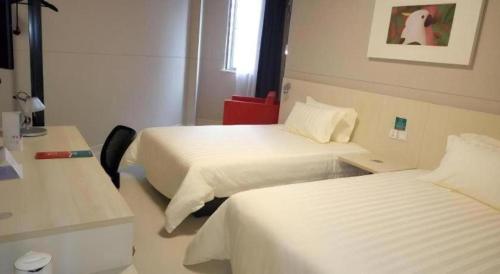 a hotel room with two beds and a desk at Jinjiang Inn Shenzhen Airport in Shenzhen