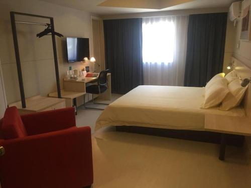 a bedroom with a bed and a chair and a window at Jinjiang Inn Jiaxing South Lake in Jiaxing