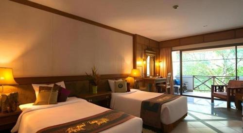 a hotel room with two beds and a balcony at River Kwai Village Hotel in Ban Kaeng Raboet