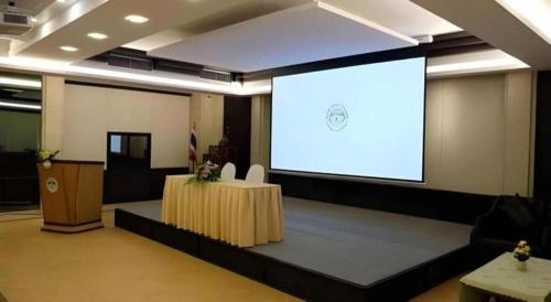 a large projection screen in a room with a stage at River Kwai Village Hotel in Ban Kaeng Raboet