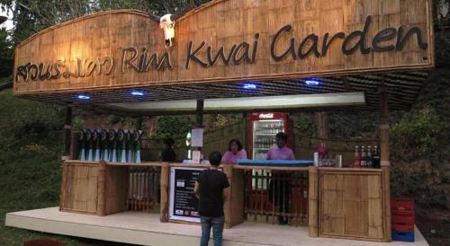 a man standing in front of a restaurant with a bar at River Kwai Village Hotel in Ban Kaeng Raboet
