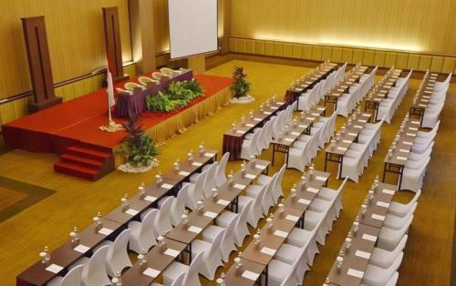 an empty hall with white chairs and a podium at The Axana Hotel in Padang