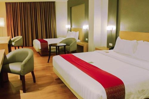 a hotel room with two beds and a chair at The Axana Hotel in Padang