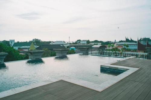 a large swimming pool with a bridge in a city at The Axana Hotel in Padang