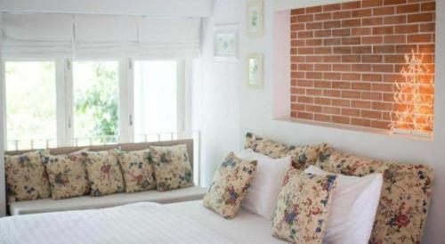 a bedroom with a bed with pillows and a brick wall at Baan Hmon-Oon in Chiang Mai