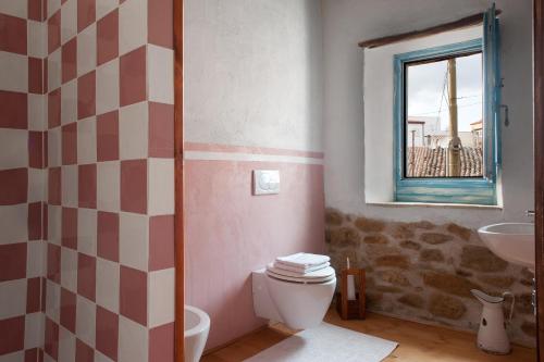 a bathroom with a toilet and a sink and a window at Domu Antiga in Gergei