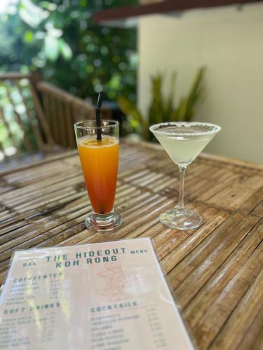 two glasses of orange juice and a drink on a table at The Hideout Koh Rong in Koh Rong