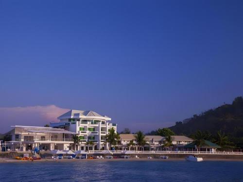 a building on the beach with boats in the water at Vitalis White Sands in Vigan