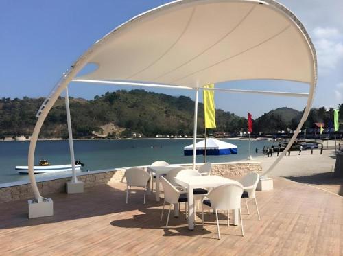 a group of tables and chairs under an arch over the water at Vitalis White Sands in Vigan