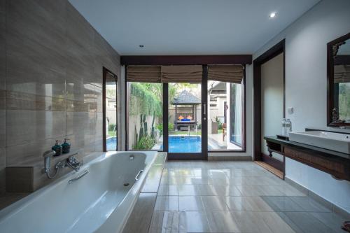 a bathroom with a tub and a large window at Aldeoz Grand Kancana Villas Resort Bali in Kerobokan