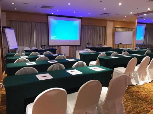 a conference room with green tables and chairs and a screen at Hotel Miramar Singapore in Singapore