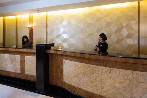 two women standing in front of a counter in a bathroom at Hotel Miramar Singapore in Singapore