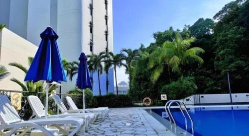 a group of chairs and umbrellas next to a pool at Hotel Miramar Singapore in Singapore