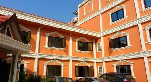 an orange building with cars parked in front of it at Khamsaner Hotel in Vientiane