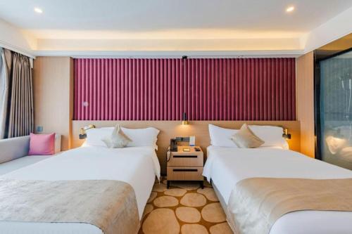 two beds in a hotel room with red walls at Yanji Yanbian International Hotel in Yanji