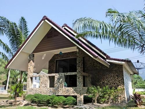a house with a palm tree in front of it at Ma-Kham Forest Resort in Nakhon Nayok