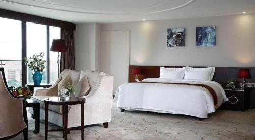 a bedroom with a white bed and a chair at SUN Yat-sen university Hotel and Conference Centre in Guangzhou