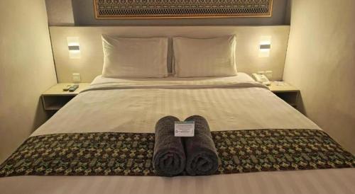 a hotel room with a bed with two pairs of slippers at Fovere Hotel Palangkaraya in Palangkaraya