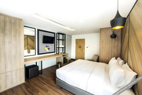 a bedroom with a large white bed and a desk at The Circle Hotel in Buriram