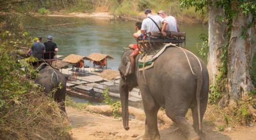 a group of people riding on the back of an elephant at The River Life Resort in Ban Kaeng Raboet