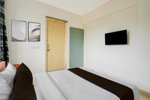 a bedroom with a bed and a tv and a door at Collection O Christ University in Kammasandra