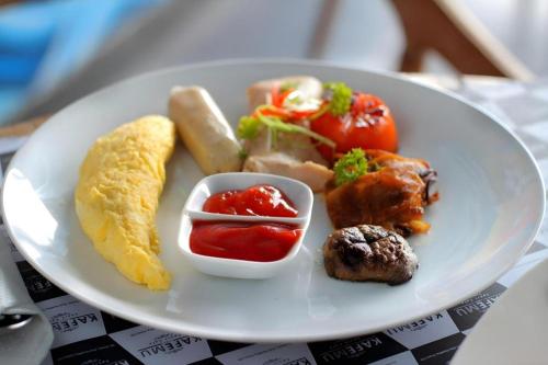 a white plate of food with breakfast foods on it at Umah Bali Suites in Denpasar